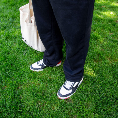 Beine, Schuhe und Tasche einer Person stehend im Rasen